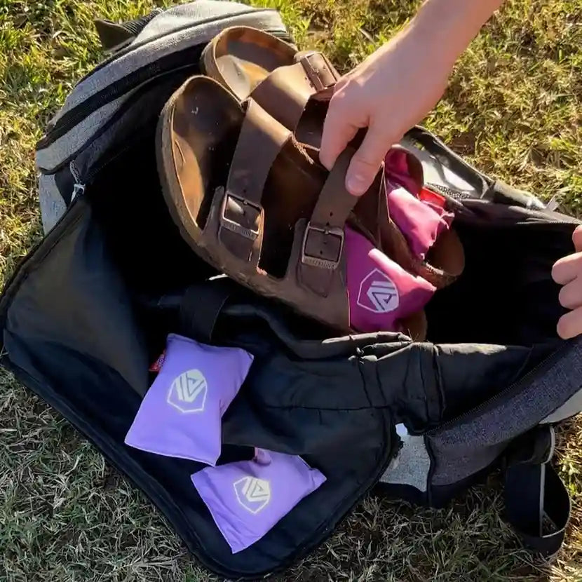 Placing Birkenstocks with Sandalwood Aroma Armour Shoe Fresheners in them into a duffel bag